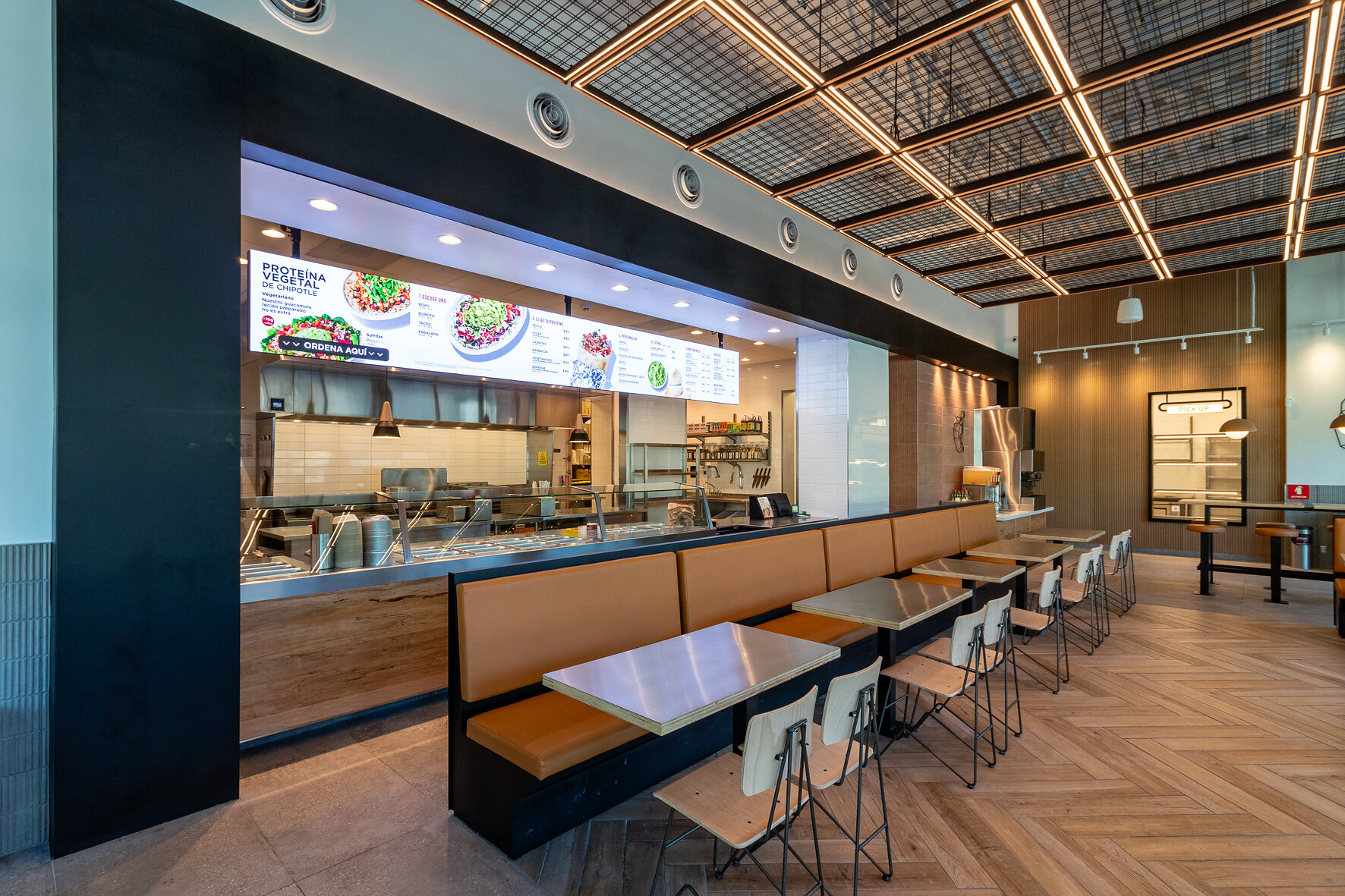 Interior del primer Chipotle de México en Plaza Fiesta San Agustín, con la barra de preparación y el menú